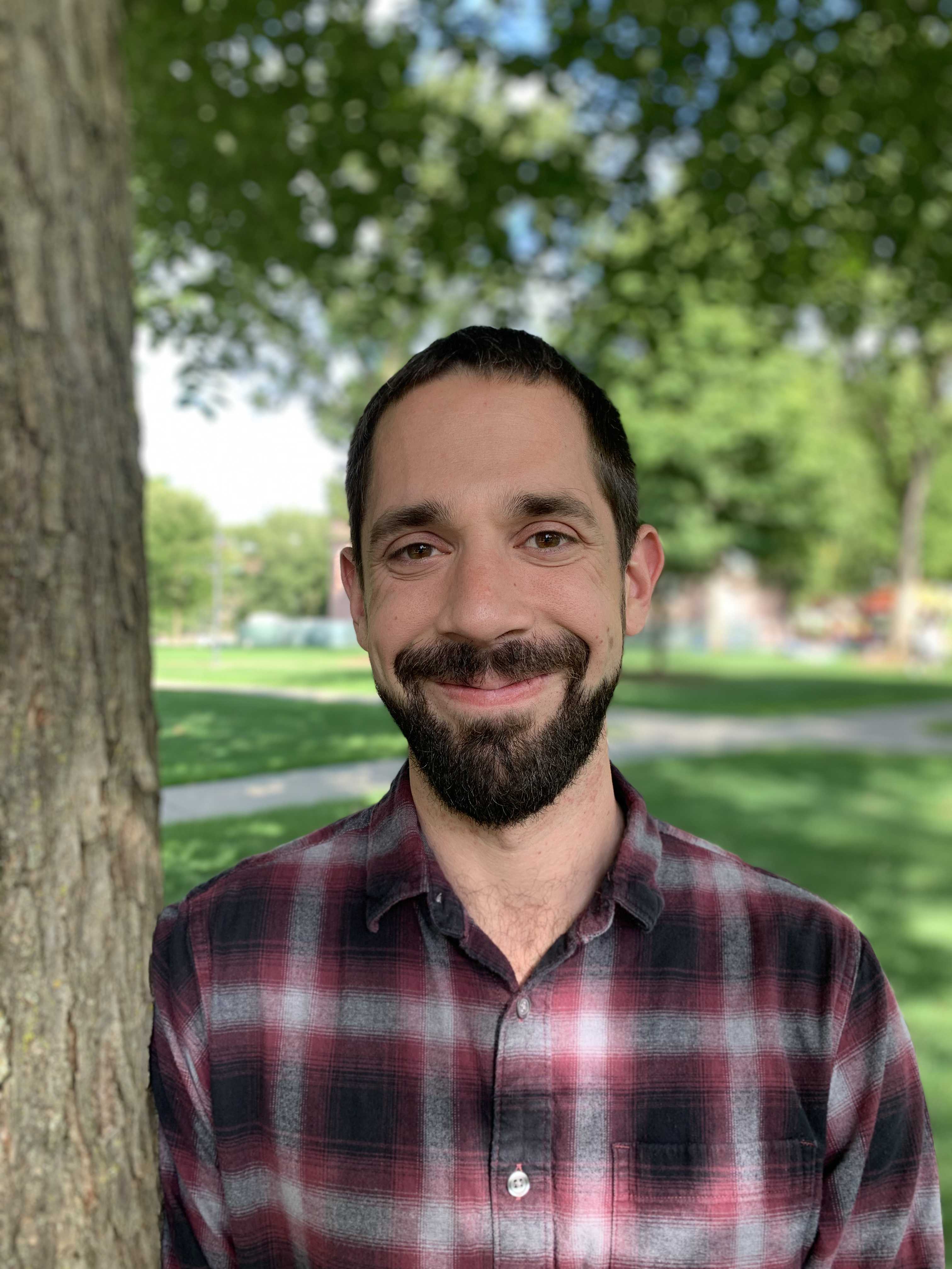 Photo of Thomas Zdyrski smiling in front
			of a tree on Dartmouth Green